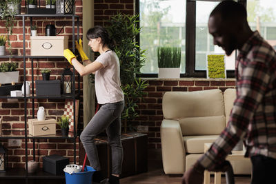 Side view of young woman using mobile phone while sitting at home