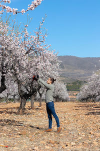 Low angle view of man standing on tree against clear sky