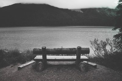 Empty bench by lake against mountain