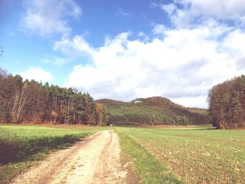 Road amidst field against sky