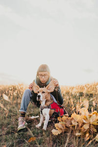 Portrait of young woman with dog on field