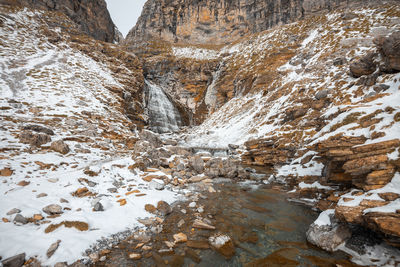 Frozen stream amidst rocks during winter