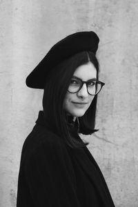 Portrait of smiling young woman standing against wall