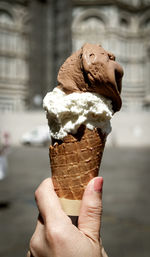 Close-up of woman hand holding ice cream cone in city