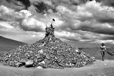 Woman walking on mountain against cloudy sky