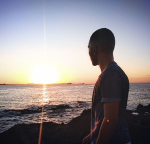 Man looking at sea against sky during sunset