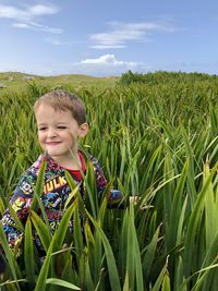 Boy standing on field against sky