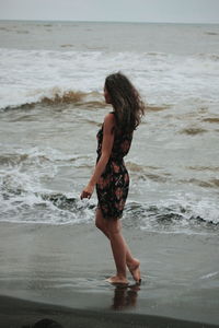 Side view of woman standing at beach