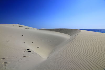 Scenic view of desert against clear blue sky