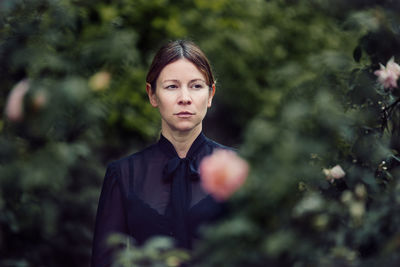 Thoughtful mid adult woman standing amidst trees in forest