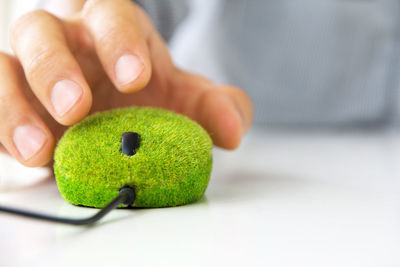 Close-up of hand holding green mouse on desk