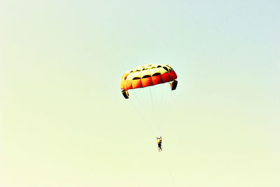 Low angle view of man paragliding against sky