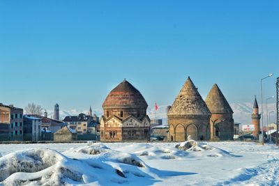 Snow covered houses against clear blue sky