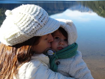 Close-up of woman kissing daughter by lake