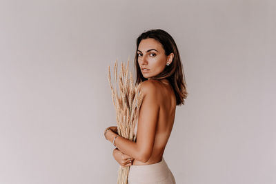 Portrait of young woman standing against white background