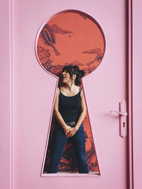 Portrait of young woman standing against wall