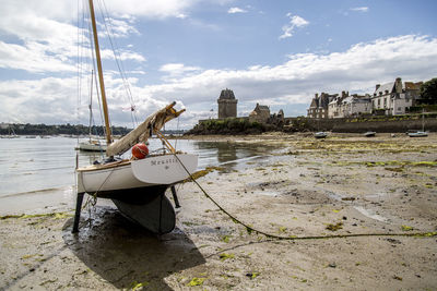 Sailboat moored on sea shore against sky