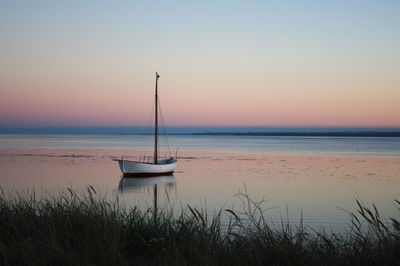 Boat moored at shore against sky during sunset