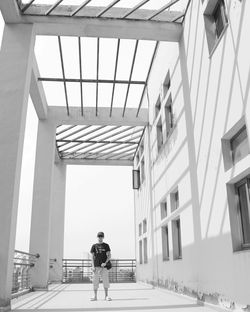 Rear view of men walking on footpath amidst buildings