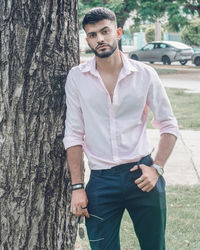 Young man standing against tree trunk