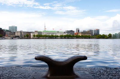 View of buildings by river against cloudy sky