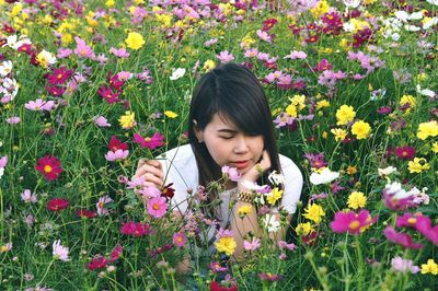 Portrait of young woman with yellow flowers in meadow