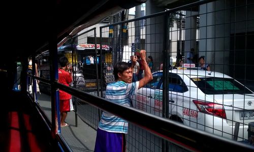 Man photographing woman standing in bus