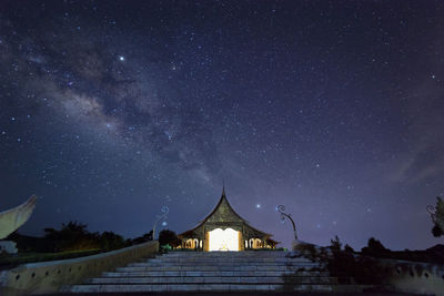 Low angle view of illuminated temple against star field at night