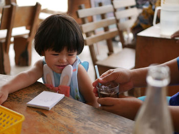 Cropped hand of person giving cold drink to girl at cafe