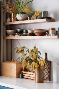 Kitchen shelves with ceramic utensils, fresh flowers and ceramic figures of mushrooms and beetles