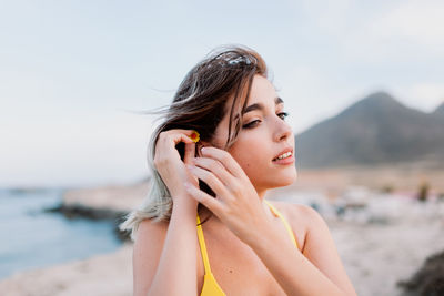 Portrait of beautiful woman on beach against sky