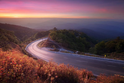 Scenic view of road by mountains against sky during sunset