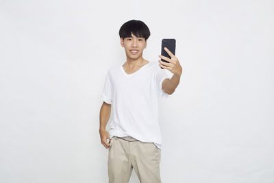 Full length of smiling man standing against white background