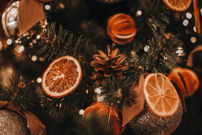 Creative christmas tree decorated with dry oranges, pine cones. magic cozy details and golden bokeh