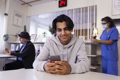 Young man sitting in waiting room and using phone