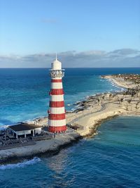 Lighthouse by sea against sky