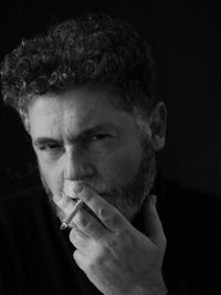 Close-up of mature man looking away against black background