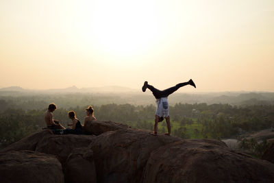 People on rock at mountain against sky