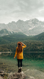 Rear view of woman looking at lake against mountain range