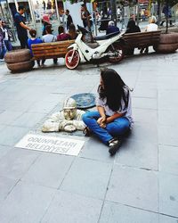 Woman sitting on sidewalk