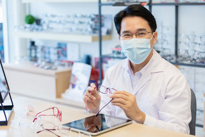 Man professional optician selling wear protective face mask sitting checking details quality.