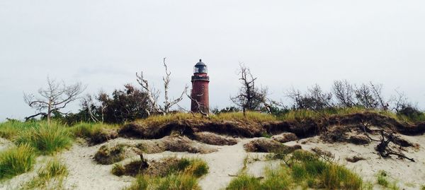 Lighthouse seen from beach against clear sky