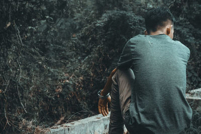 Rear view of man sitting against plants