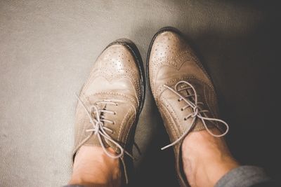Low section of person wearing brown leather shoes