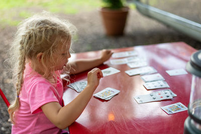 Rear view of girl sitting on table