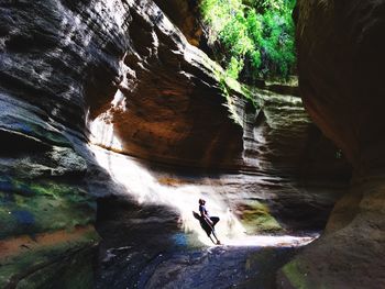 Full length of woman leaning on rock formation in cave