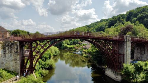 Ironbridge over river amidst trees against sky