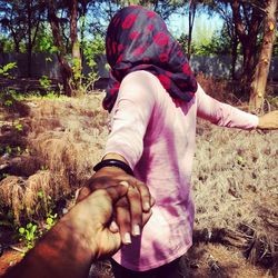 Cropped image of boyfriend holding girlfriend hand in forest
