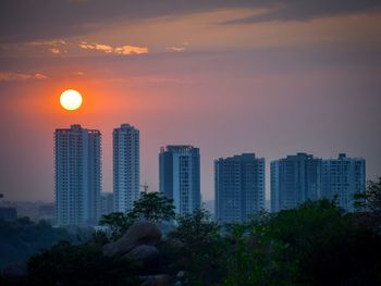 Modern buildings against sky during sunset