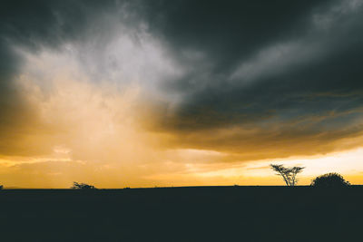 Silhouette landscape against cloudy sky during sunset